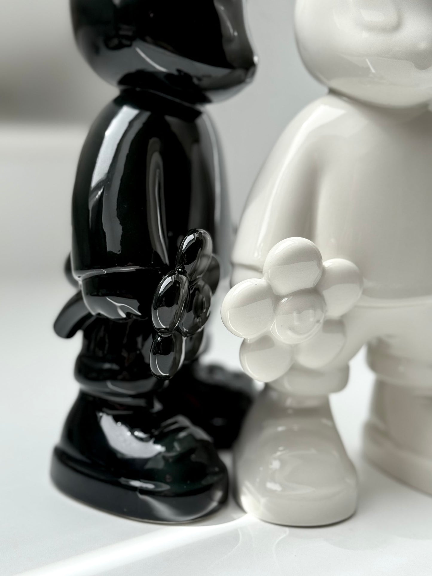 BUNBUN’S HAPPY FLOWER - collectible art toy sculpture. Close up of black and white ceramic BUNBUN art toy holding a flower.