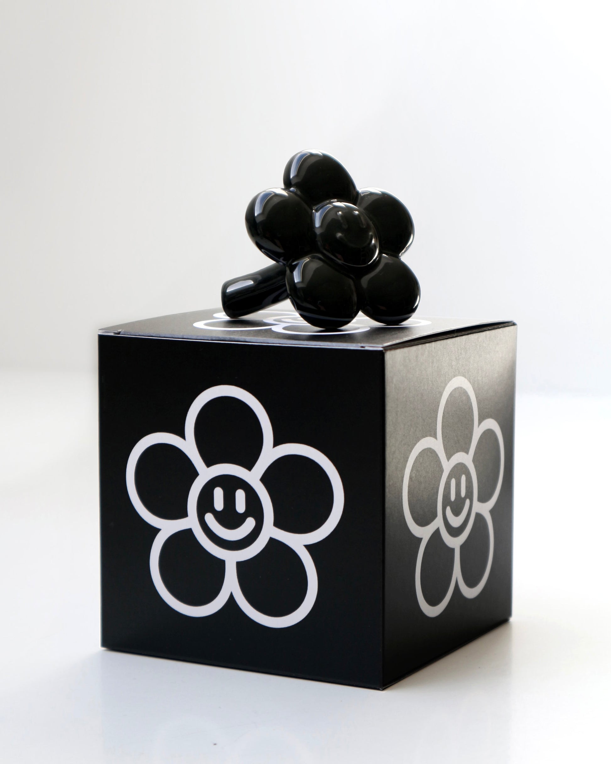 BUNBUN’S HAPPY FLOWER - collectible art toy sculpture. Black flower-shaped figurine on top of a branded box.